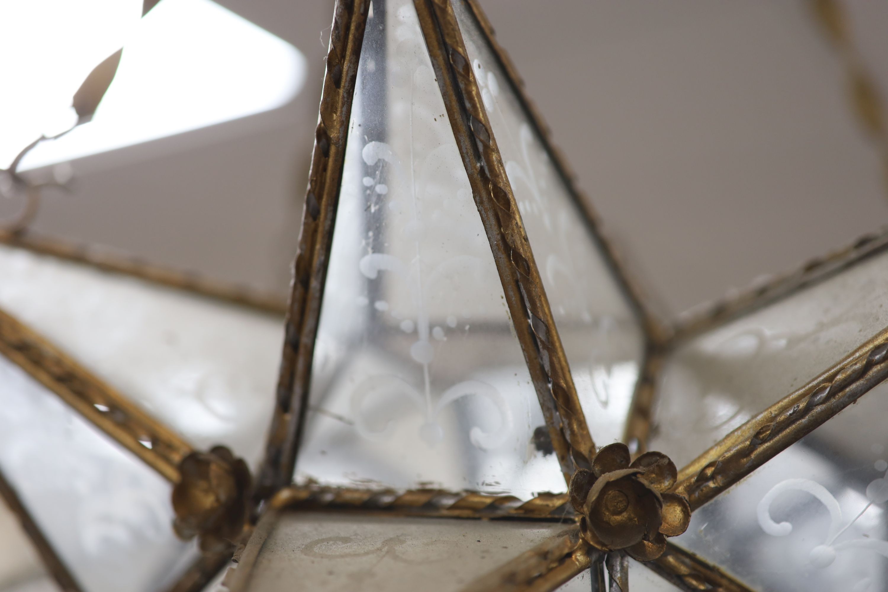 A gilt-metal star-shaped ceiling light, having etched plain glass panels and chain suspension, height 80cm